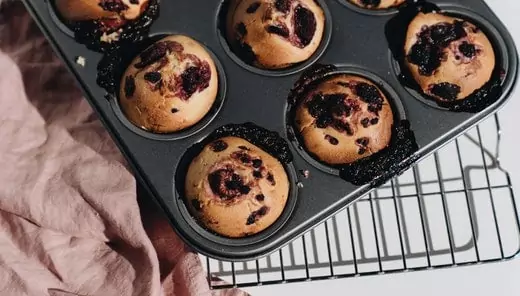 The picture contains lots of blueberry muffins in a baking tray, which is a vegan breakfast food that starting with m.